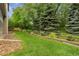 Lush backyard featuring a manicured lawn, mature trees, and decorative rock landscaping and a section of wood fence at 1831 Ashford Cir, Longmont, CO 80504