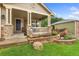 Inviting front porch with stone pillars and a quaint seating area surrounded by landscaping at 1831 Ashford Cir, Longmont, CO 80504