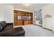Bright room with large custom bookcase, love seat and neutral carpet at 1831 Ashford Cir, Longmont, CO 80504