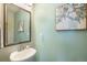 Stylish powder room with pedestal sink, neutral color palette and decorative mirror and artwork at 17996 E 54Th Ave, Denver, CO 80249