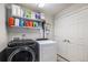 Laundry room with modern washer and dryer, white shelving, and double door storage at 17996 E 54Th Ave, Denver, CO 80249
