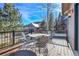 Outdoor deck area with metal patio set overlooking trees and neighborhood homes on a sunny day at 1294 Red Lodge Dr, Evergreen, CO 80439