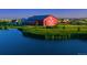 Lakeside view of a red barn with white trim, surrounded by a green lawn and lush vegetation at 10480 Truckee St # B, Commerce City, CO 80022