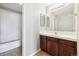 Neutral bathroom featuring a tiled countertop vanity with dark wood cabinets, a large mirror, and a tiled shower at 10480 Truckee St # B, Commerce City, CO 80022