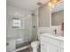 Bathroom featuring glass shower, gray accent wall, white vanity, decorative light fixture, and brushed metal hardware at 5172 S Cody Ct, Littleton, CO 80123
