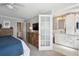 Light-filled main bedroom with wood dresser, ceiling fan, plush carpet, and an ensuite bath with frosted glass door at 5172 S Cody Ct, Littleton, CO 80123
