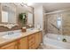 Bathroom featuring double sinks, framed mirrors, tub, and tiled shower at 10056 W Unser Dr # 102, Littleton, CO 80127
