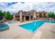 Community pool with a hot tub and lounge chairs next to a clubhouse with stone pillars at 10056 W Unser Dr # 102, Littleton, CO 80127