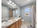 Bright bathroom with a double sink vanity, shower-tub combo, and a window with a scenic view at 14711 Detroit Way, Thornton, CO 80602