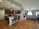 Open-concept kitchen and living room featuring hardwood floors, dark wood cabinets, and granite countertops at 14545 Barksdaly Way, Keenesburg, CO 80643