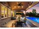 Inviting outdoor patio with a dining table, ceiling fan, and an outdoor kitchen overlooking the pool at 3749 White Bay Dr, Highlands Ranch, CO 80126
