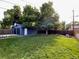 A spacious backyard with a lush green lawn, tall trees, and a detached garage at 1335 S Holly St, Denver, CO 80222