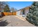 Exterior shot of house featuring paved driveway, fenced yard, and mature evergreens at 1335 S Holly St, Denver, CO 80222