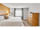 Comfortable bedroom featuring wood accent wall, neutral paint, large window, and wood dresser at 5374 W Canyon Trl # B, Littleton, CO 80128