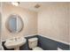 Half bathroom with decorative wallpaper, a pedestal sink, and a stylish mirror at 7844 S Eudora Cir, Centennial, CO 80122