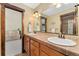Bathroom with double sinks, tiled countertops and wood trim with an adjoining room visible at 3048 Starling Ct, Castle Rock, CO 80109