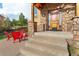 Inviting front porch with stone pillars, wooden door and trim, and comfortable red Adirondack chairs for relaxing in the Colorado sun at 3048 Starling Ct, Castle Rock, CO 80109