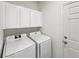 A well-lit laundry room that has a washer, dryer, and upper cabinets for storage at 11933 W 83Rd Ln, Arvada, CO 80005