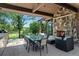 Covered outdoor living space featuring a stone fireplace, dining area, and serene views of the yard at 5 Random Rd, Cherry Hills Village, CO 80113