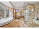 Bathroom with dual head shower, soaking tub, and natural stone finishes on the walls and floors at 5 Random Rd, Cherry Hills Village, CO 80113