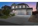 Two-story house with gray siding, stone accents, and a three-car garage at dusk at 7478 Oasis Dr, Castle Rock, CO 80108