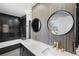 Stunning bathroom with dual sinks, wood accent wall, and modern black tiled shower and tub at 13254 E Asbury Dr, Aurora, CO 80014