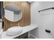 Stylish powder room featuring an eye-catching round mirror, vessel sink, and wood slat accent wall at 13254 E Asbury Dr, Aurora, CO 80014