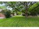 View of the spacious backyard featuring lush green grass and mature trees for shade at 4 Doral Ln, Littleton, CO 80123