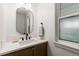 Bathroom vanity with wood cabinets, black hardware, stone countertop, and a modern mirror at 4 Doral Ln, Littleton, CO 80123