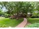Well-manicured front yard featuring mature tree, lush lawn, and brick walkway leading to a welcoming home at 4 Doral Ln, Littleton, CO 80123