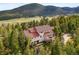 Expansive aerial shot of a grand home nestled in a lush, green forest setting at 1425 Autumnwood Ln, Evergreen, CO 80439