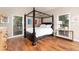 Bedroom featuring a four-poster bed, hardwood floors, and natural light from two windows at 1425 Autumnwood Ln, Evergreen, CO 80439