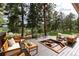 Cozy outdoor patio with a built-in fire pit and comfortable seating, surrounded by mature trees at 1425 Autumnwood Ln, Evergreen, CO 80439