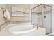 A relaxing bathroom features a soaking tub, glass-enclosed shower with mosaic tile accents, and decorative artwork at 9528 Pendio Ct, Highlands Ranch, CO 80126