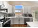 Modern kitchen featuring white cabinetry, stainless steel appliances, and a window overlooking the backyard at 2209 Lupine Pl, Erie, CO 80516
