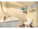 Clean bathroom featuring a sink, toilet, mirror, and wall shelving at 2564 S Acoma St, Denver, CO 80223