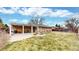 Wide angle view of a backyard with a built in patio, fire pit, Adirondack chairs, and a large grassy area at 1823 S Carr St, Lakewood, CO 80232