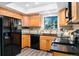 Well-lit kitchen with black appliances, wood cabinets, and a functional layout at 10836 W Evans Ave # 29, Lakewood, CO 80227