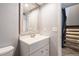 Bathroom with white vanity, modern fixtures, and a decorative mirror and adjacent to the stairway at 2314 S Troy St, Aurora, CO 80014