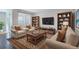 Staged living room features hardwood floors, a comfortable seating arrangement, and built-in bookshelves at 4238 S Netherland Cir, Aurora, CO 80013