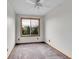 A vacant bedroom with neutral carpet, a ceiling fan, and a large window providing plenty of natural light at 6343 Laguna Cir, Highlands Ranch, CO 80130