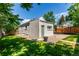 View of backyard with a concrete patio and small garden area surrounded by green grass at 4450 S Fox St, Englewood, CO 80110