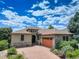 Front exterior of home with brick driveway, stone accents, lush landscaping, and three car garage at 11208 W Ontario Ave, Littleton, CO 80127