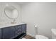 Stylish powder room with modern fixtures, a round mirror, and a navy vanity with gold hardware at 8023 Gore Creek Ln, Littleton, CO 80125