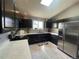 Modern kitchen featuring dark cabinetry, stainless steel appliances, and ample counter space at 13660 Monroe St, Thornton, CO 80602