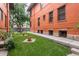 A well-maintained green backyard featuring lush grass and potted plants next to the red brick building at 1401 N Franklin St # 2, Denver, CO 80218