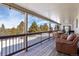 Covered deck with seating area and string lights, overlooking snowy landscape and evergreen trees at 6834 Hillside Way, Parker, CO 80134