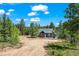 Exterior of home with gravel driveway and natural, wooded surroundings at 10411 Dowdle Dr, Golden, CO 80403