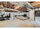 Unfinished basement with exposed beams, pool table, seating area, and recreational equipment, offering potential for customization at 5181 Delphinium Cir, Brighton, CO 80601