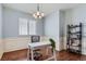 Bright home office with hardwood floors, wainscoting, chandelier, desk, and shelving at 5181 Delphinium Cir, Brighton, CO 80601